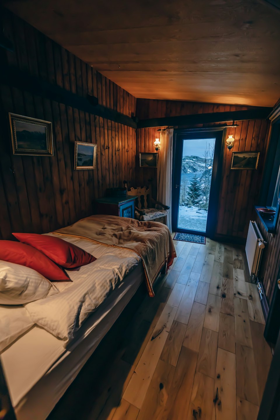Ein rustikales Schlafzimmer mit weißer Bettwäsche blickt auf eine verschneite Landschaft.