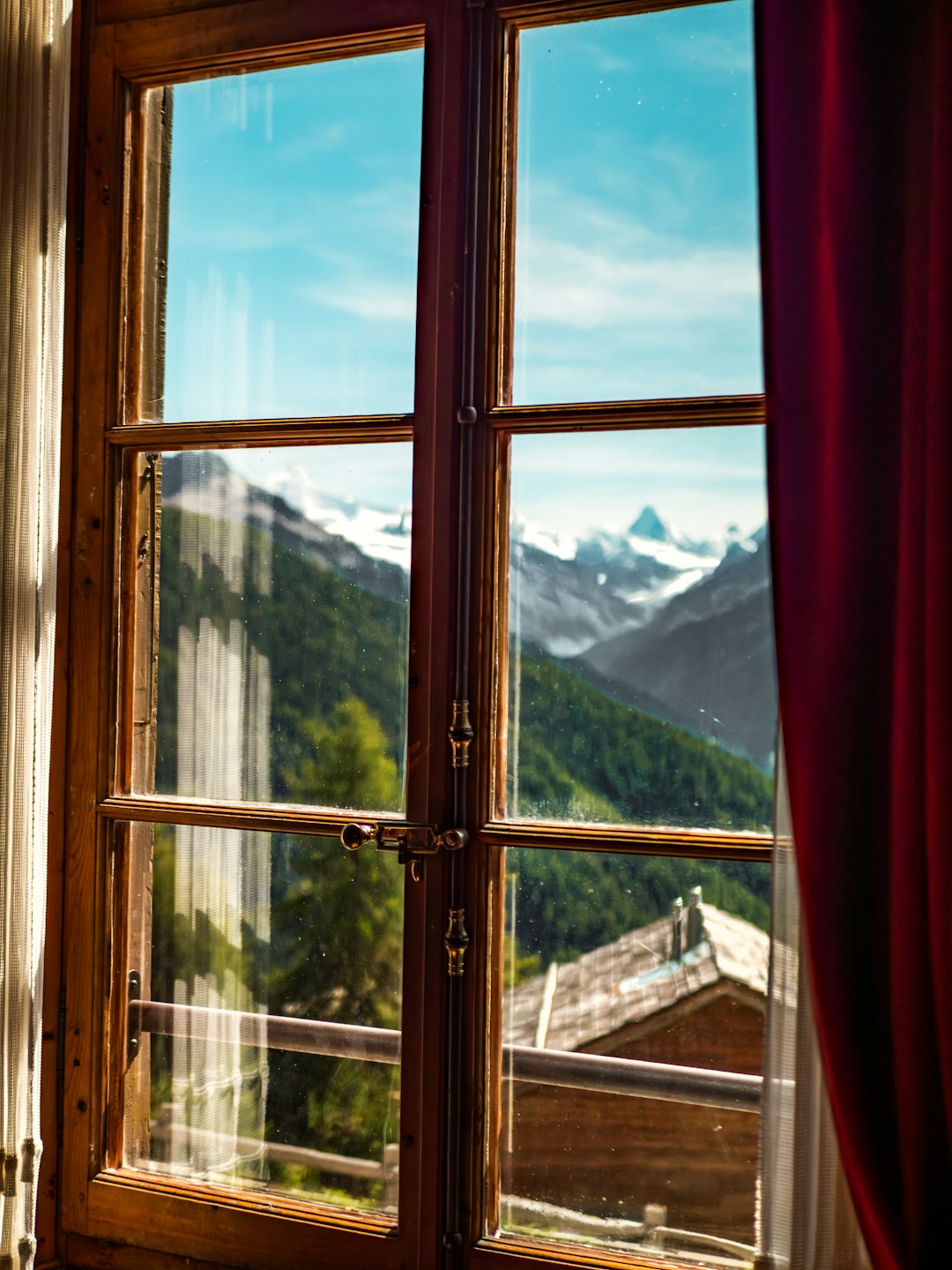 Schneebedeckte Berge und ein Wald durch ein Fenster.