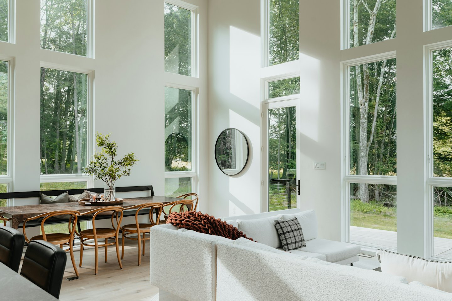 Modernes Wohn- und Esszimmer mit großen Fenstern und Waldblick.